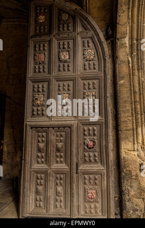 Porte en bois, aux écoles de la Bodleian Library Quadrangle porte le blason de plusieurs collèges de l'Université d'Oxford, Royaume-Uni. Banque D'Images