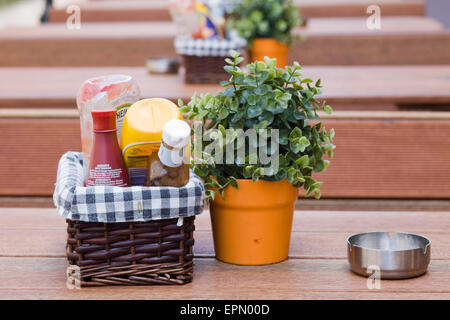 Les Condiments dans un panier en osier sur une table à manger Banque D'Images