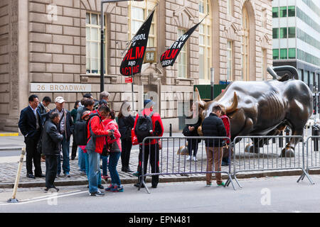 Des touristes posent pour photos de la statue de taureau Charge à Broadway dans le quartier financier de la ville de New York. Banque D'Images
