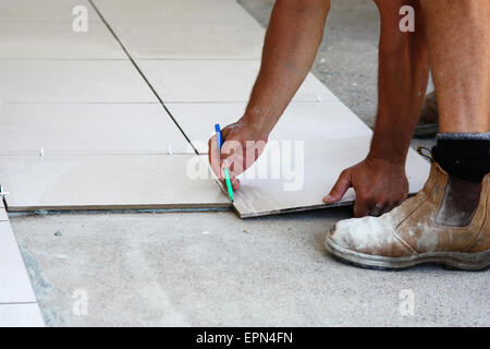 Un homme pose de carrelage de sol en céramique sur une maison Banque D'Images