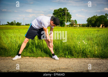 Athletic, beau jeune homme fit en plein air pays fait des exercices d'étirement Banque D'Images