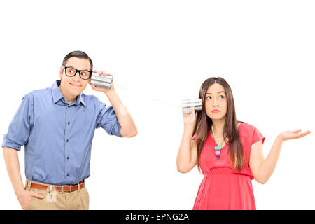 Jeune couple parler à travers une boîte téléphone. La femme est la confusion des gestes et l'homme est souriant et l'écoute Banque D'Images