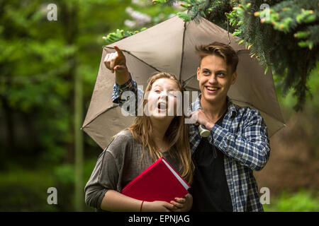 Jeune garçon et une fille sous un parapluie à l'extérieur. Banque D'Images