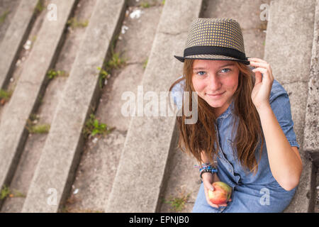 Jeune fille assise sur les marches de pierre, vue du dessus, en regardant la caméra. Banque D'Images