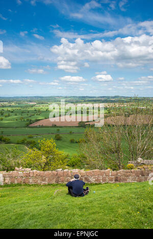 Un homme âgé est assis en profitant de la vue du château de Beeston Cheshire sur une belle journée de printemps ensoleillée. Banque D'Images