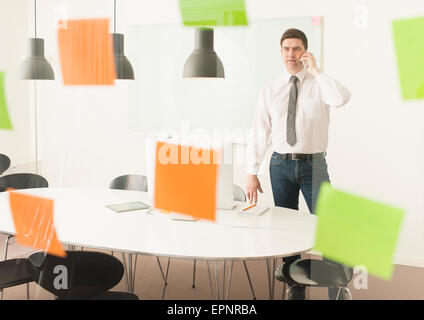 Businessman looking at paroi en verre avec des notes adhésives. Image conceptuelle de la planification d'entreprise. Banque D'Images