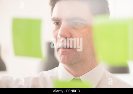 Businessman looking at paroi en verre avec des notes adhésives. Image conceptuelle de la planification d'entreprise. Banque D'Images