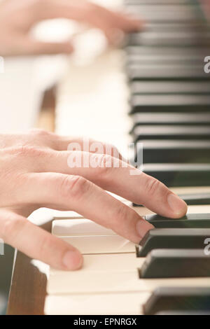 Près des mains de l'homme jouer du piano Banque D'Images