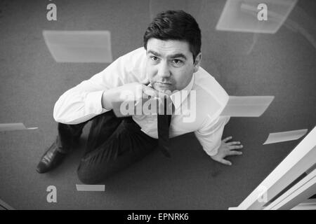 Businessman sitting on office-de-chaussée à la recherche jusqu'au mur de verre avec des notes adhésives. Image conceptuelle de la planification d'entreprise et Banque D'Images