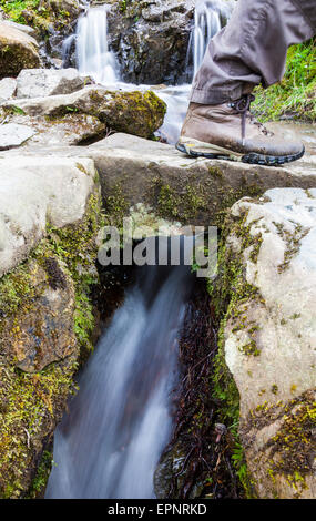 Le pied d'un déambulateur pour traverser un petit pont sur le sentier public aux côtés de l'Aira Beck, près de l'Aira Force, Lake District, Cumbria Banque D'Images