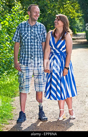 Beau mobilité homme portant une jambe artificielle debout avec sa jeune amie de sa belle sur un chemin rural, en souriant. Banque D'Images