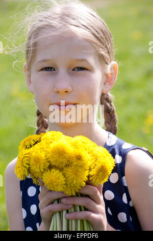 Young pretty caucasian Girl standing avec pissenlits jaunes dans les mains, face closeup Banque D'Images