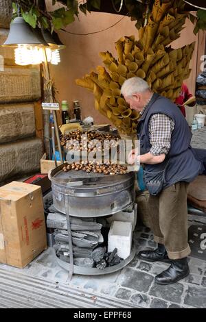 Vendeur de rue de la torréfaction châtaignes sur un brasero dans une rue de Rome, Italie. Banque D'Images