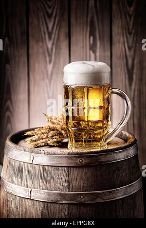 Chope de bière légère avec de la mousse et d'un tonneau en bois épillets Banque D'Images