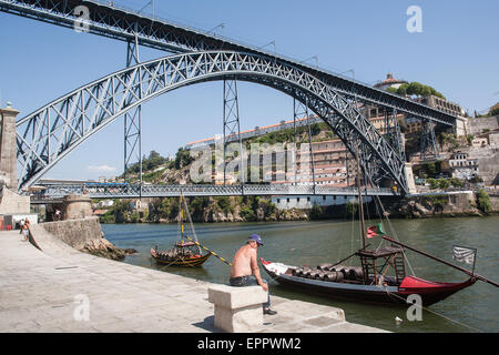 Pont Dom Luis I, dont au niveau supérieur est à la fois une passerelle et une ligne de métro et des voitures sur le niveau inférieur, de Ribeira, sur la rive nord de la rivière Douro. Les chalands amarrés ont des anciens tonneaux de vin de Porto. Porto, Portugal. Banque D'Images