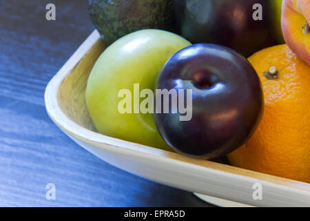 Bol de fruits prune, avocat, pomme, orange, etc. Banque D'Images