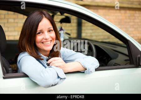 Jeune femme à la sortie de sa voiture ses clefs holding fenêtre Banque D'Images