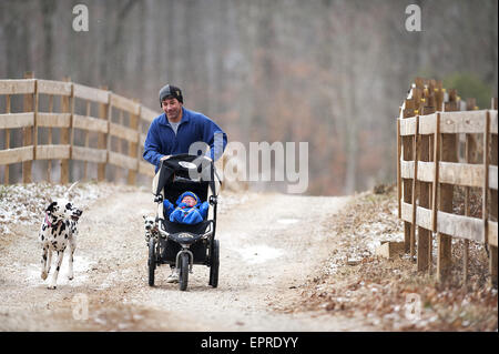 Un homme gère avec son fils dans une poussette de jogging avec son chien dans le Tennessee. Banque D'Images