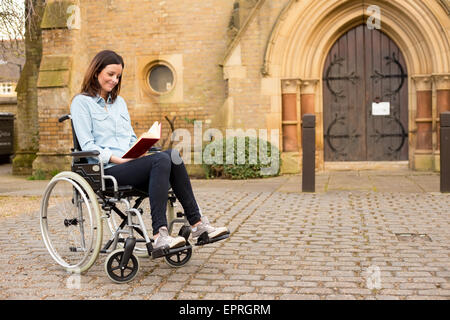 Une jeune personne en fauteuil roulant la lecture d'une bible Banque D'Images