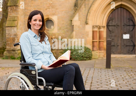 Utilisateur de fauteuil roulant tenant une bible Banque D'Images