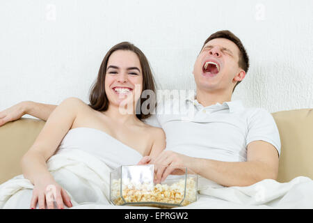 Heureux jeune beau couple assis sur le canapé dans la salle de séjour à la maison couverte de couverture et regarder comédie fanny récept sur Banque D'Images