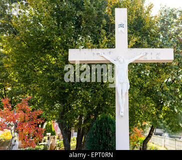 La grande croix blanche en bois avec Jésus Christ crucifié statue à la montagne de l'apparition de Medjugorje parmi les arbres verts et les mauvaises herbes Banque D'Images