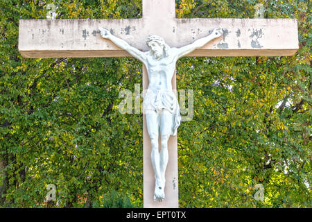 La grande croix blanche en bois avec Jésus Christ crucifié statue à la montagne de l'apparition de Medjugorje parmi les arbres verts et les mauvaises herbes Banque D'Images