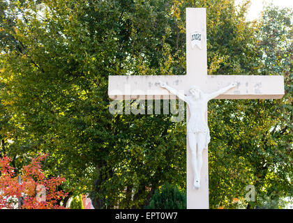 La grande croix blanche en bois avec Jésus Christ crucifié statue à la montagne de l'apparition de Medjugorje parmi les arbres verts et les mauvaises herbes Banque D'Images