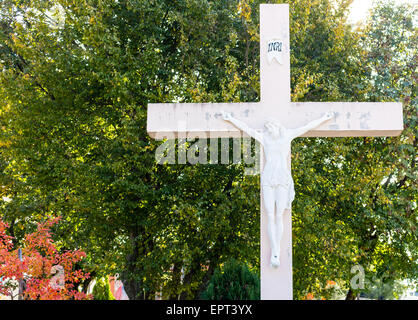 La grande croix blanche en bois avec Jésus Christ crucifié statue à la montagne de l'apparition de Medjugorje parmi les arbres verts et les mauvaises herbes Banque D'Images