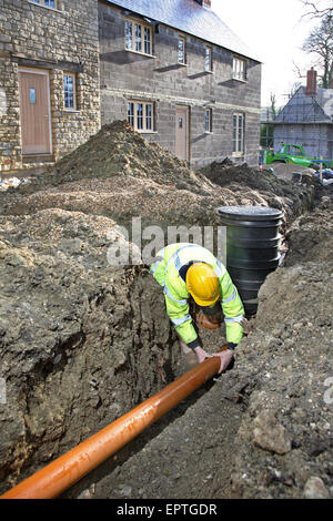 Les travailleurs de la construction d'un connecte un tuyau de drainage en plastique à une chambre d'inspection sur un développement de l'habitat rural dans le Dorset, UK Banque D'Images