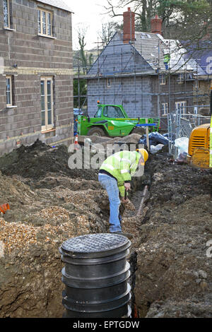 Un travailleur de la construction pose des tuyaux de drainage souterrain en plastique sur un petit développement de l'habitat rural dans le Dorset, UK Banque D'Images