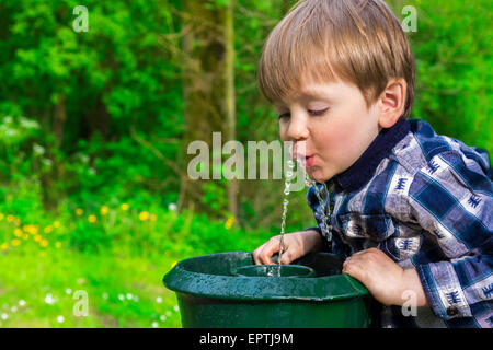 Cute little boy drinking from une fontaine Banque D'Images