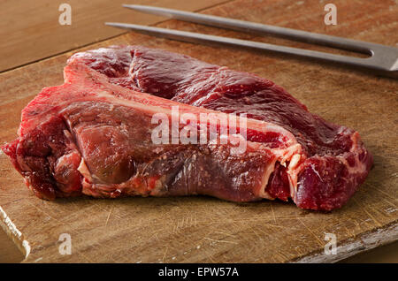 Le boeuf cru t-bone steak sur la table en bois sombre. Banque D'Images