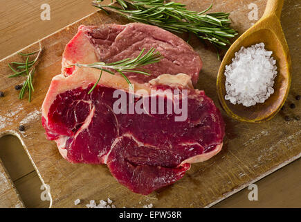 Le boeuf cru t-bone steak sur la vieille planche de bois. Banque D'Images