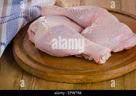 Cuisses de poulet crus sur une planche à découper en bois. Banque D'Images