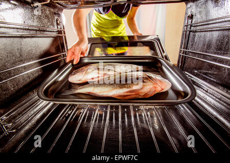 Ménagère prépare dorado poisson au four, vue de l'intérieur du four. La cuisson au four. Banque D'Images