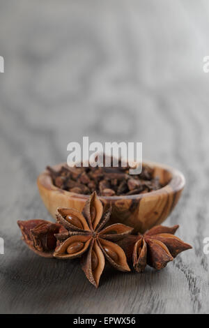 Étoiles d'anis dans un bol d'olive sur table en chêne rustique, Banque D'Images
