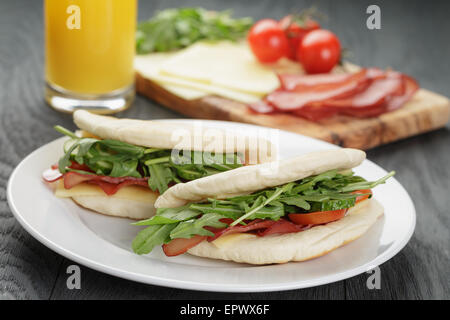 Deux sandwichs au jambon tomates et roquette dans le pain pita sur plaque, sur table en bois Banque D'Images