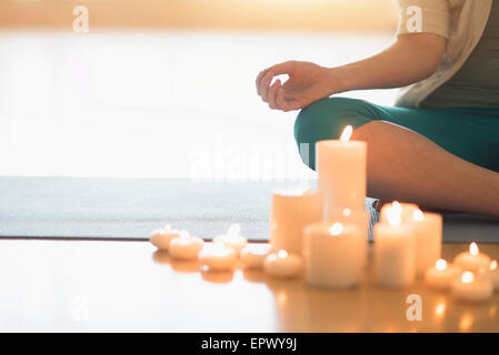 Woman meditating entourée de bougies Banque D'Images