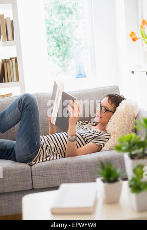 Senior woman reading book on sofa Banque D'Images