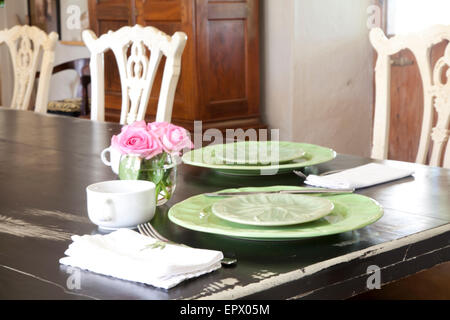 Table dressée avec de la vaisselle vert, vase de roses roses et blancs en Afrique du Sud home tasses Banque D'Images