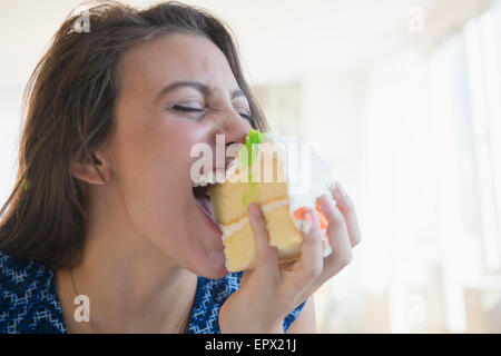 Woman biting morceau de gâteau Banque D'Images