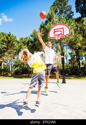 Boy (8-9) en jouant au basket avec son frère Banque D'Images