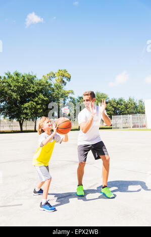 Boy (8-9) en jouant au basket avec son frère Banque D'Images