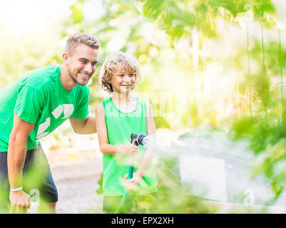 Boy (8-9) d'arroser les plantes avec son frère Banque D'Images