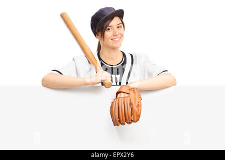 Jeune femme en tenue de sport une batte de baseball et le port d'un gant de baseball et posant derrière un panneau vierge Banque D'Images