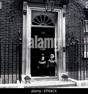 Années 1950, historiques, deux petits enfants debout, tenant la main à l'extérieur de l'entrée au 10, Downing Street, Westminster, London, résidence officielle du Premier Ministre britannique. Banque D'Images