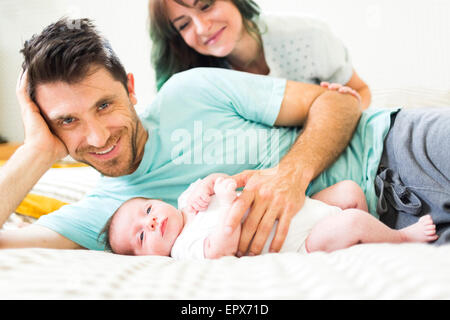 Heureux parents avec bébé garçon (6-11 mois) lying on bed Banque D'Images