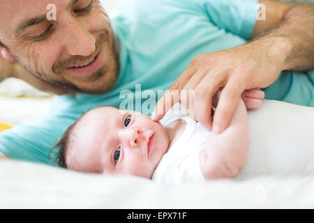 Père avec bébé garçon (6-11 mois) on bed Banque D'Images