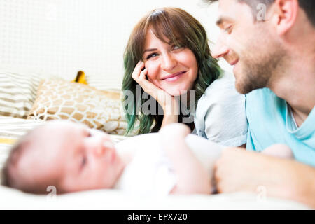 Heureux parents avec bébé garçon (6-11 mois) on bed Banque D'Images